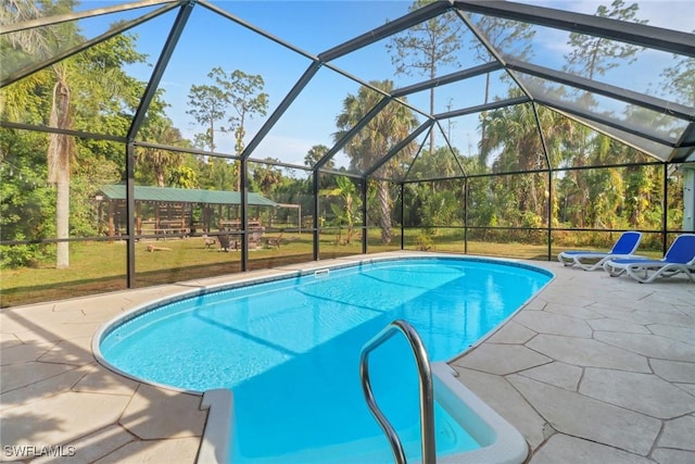 view of pool with glass enclosure and a patio area