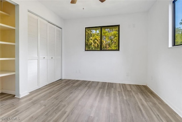 unfurnished bedroom with ceiling fan, light hardwood / wood-style flooring, multiple windows, and a closet