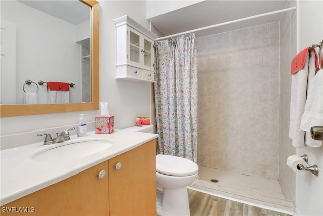 bathroom with hardwood / wood-style floors, vanity, toilet, and walk in shower