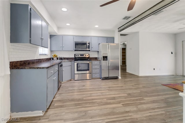 kitchen with light wood-type flooring, backsplash, stainless steel appliances, ceiling fan, and gray cabinets