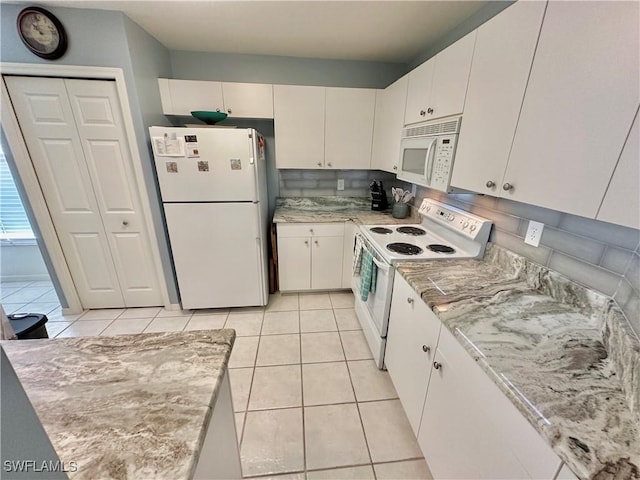 kitchen featuring decorative backsplash, light tile patterned floors, white cabinets, and white appliances