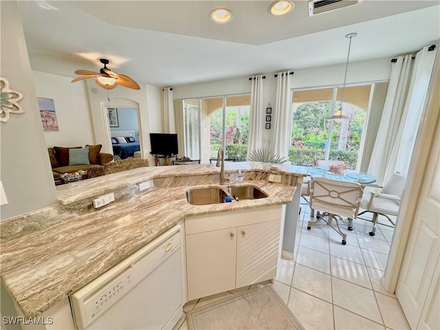 kitchen with dishwasher, sink, light stone counters, light tile patterned flooring, and white cabinets