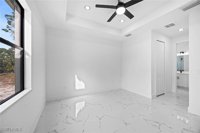 spare room featuring ceiling fan, a raised ceiling, and sink