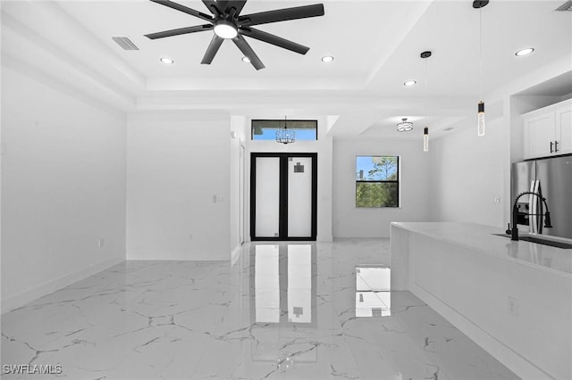 foyer with ceiling fan, sink, and a tray ceiling