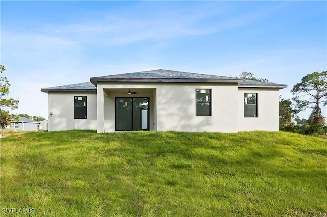 rear view of property with a lawn and ceiling fan