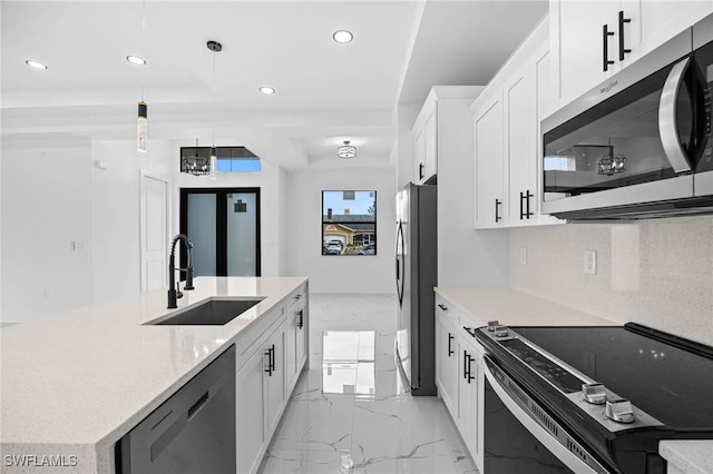 kitchen with a kitchen island with sink, white cabinets, sink, hanging light fixtures, and stainless steel appliances