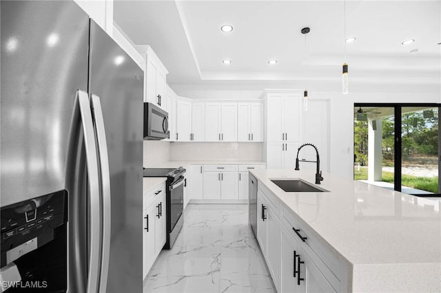 kitchen featuring appliances with stainless steel finishes, decorative light fixtures, and white cabinetry