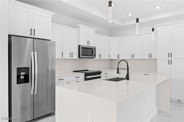 kitchen with a center island with sink, light stone countertops, appliances with stainless steel finishes, decorative light fixtures, and white cabinetry