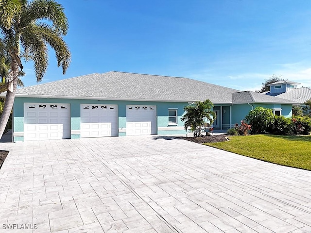 ranch-style home featuring a garage, a front lawn, decorative driveway, and stucco siding