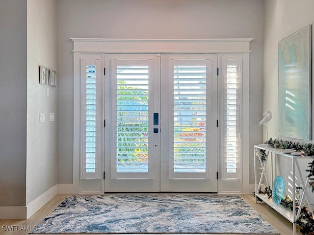 foyer entrance with light wood-type flooring, french doors, plenty of natural light, and baseboards