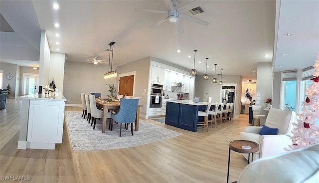 dining space featuring ceiling fan, light wood-type flooring, and sink