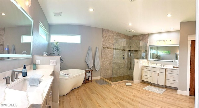 bathroom with a sink, a stall shower, wood finished floors, and a soaking tub