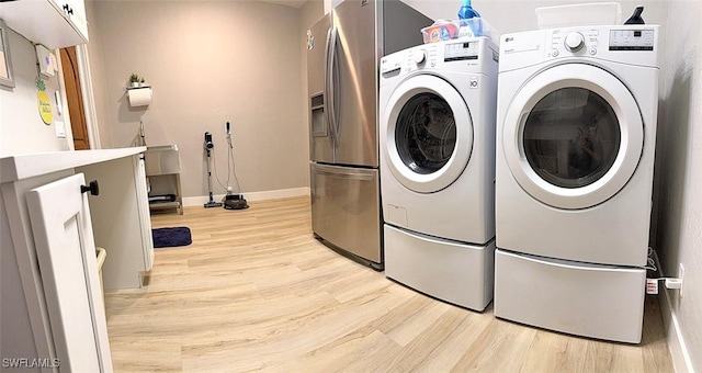 laundry area with laundry area, light wood-type flooring, washing machine and clothes dryer, and baseboards