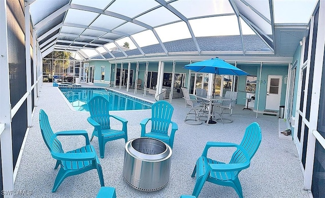 view of swimming pool featuring an outdoor fire pit, a pool with connected hot tub, glass enclosure, and a patio