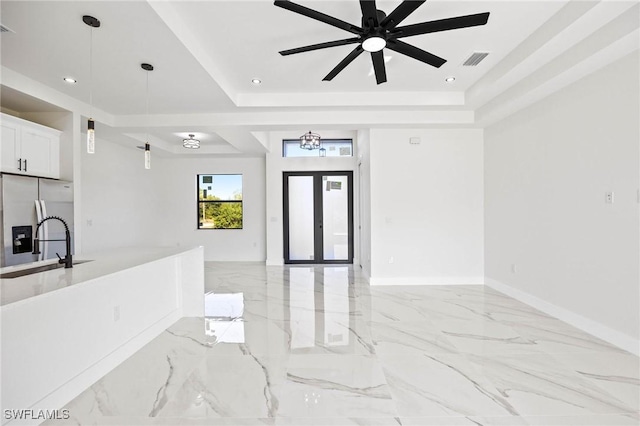 interior space with white cabinets, a raised ceiling, sink, stainless steel refrigerator with ice dispenser, and ceiling fan