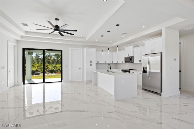 kitchen with white cabinets, hanging light fixtures, ceiling fan, an island with sink, and appliances with stainless steel finishes