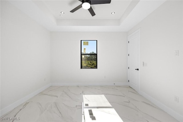 empty room featuring a tray ceiling and ceiling fan