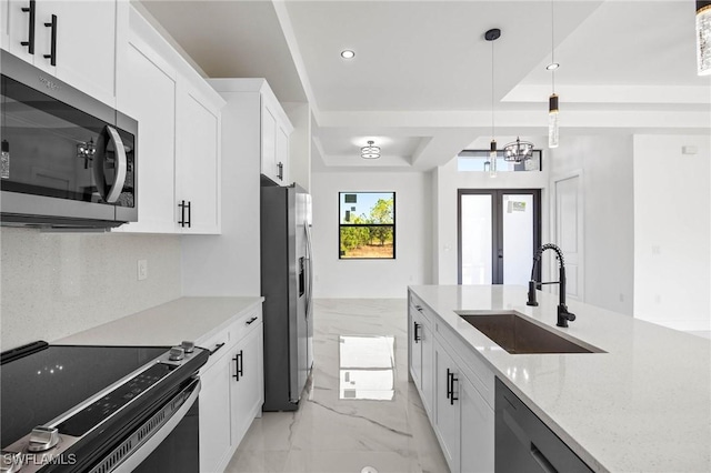 kitchen with sink, hanging light fixtures, stainless steel appliances, light stone counters, and white cabinets