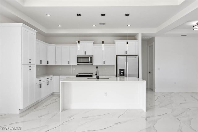 kitchen with pendant lighting, stainless steel appliances, a kitchen island with sink, and sink