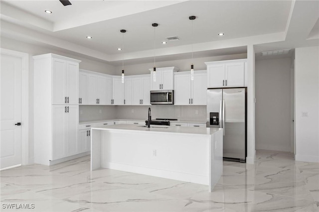 kitchen with white cabinets, hanging light fixtures, an island with sink, and appliances with stainless steel finishes