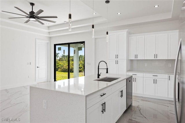 kitchen featuring white cabinets, a raised ceiling, a kitchen island with sink, and stainless steel dishwasher