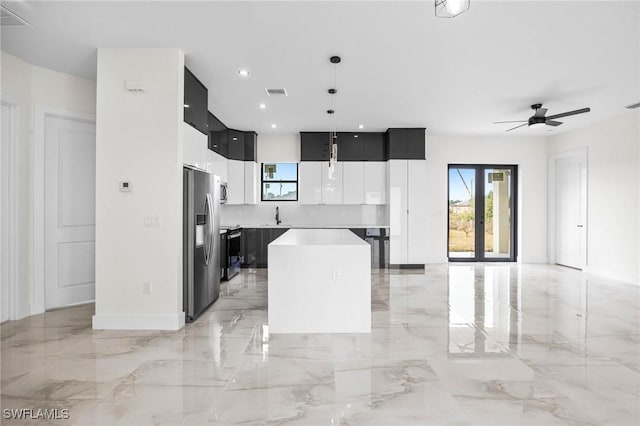 kitchen with ceiling fan, a center island, sink, stainless steel fridge with ice dispenser, and decorative light fixtures