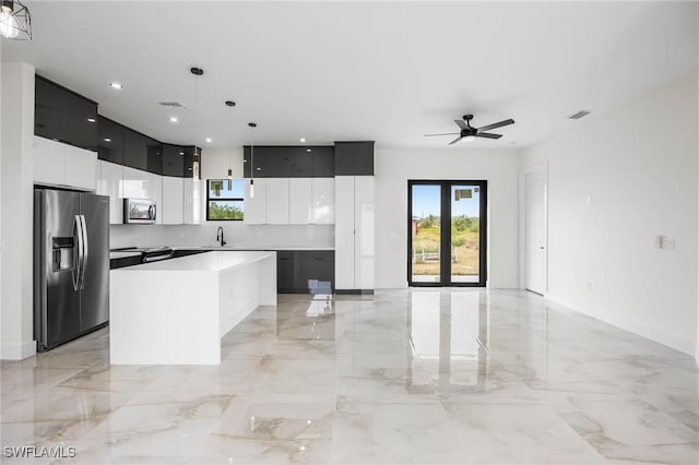 kitchen featuring ceiling fan, sink, decorative light fixtures, a kitchen island, and appliances with stainless steel finishes