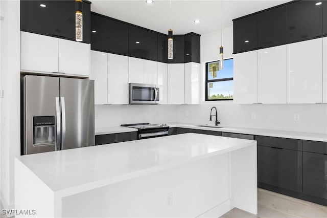 kitchen with white cabinets, sink, decorative light fixtures, a kitchen island, and stainless steel appliances