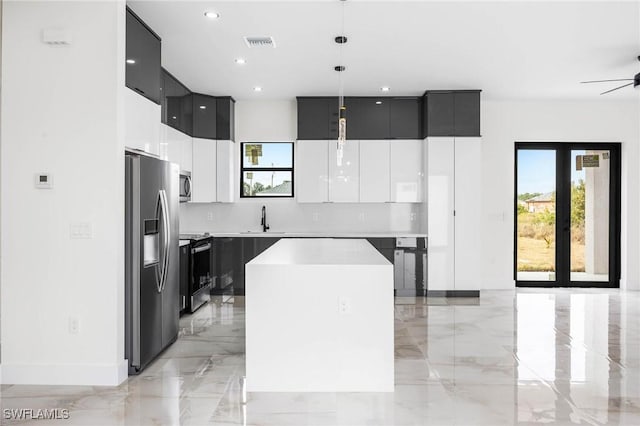 kitchen featuring appliances with stainless steel finishes, ceiling fan, sink, a center island, and hanging light fixtures