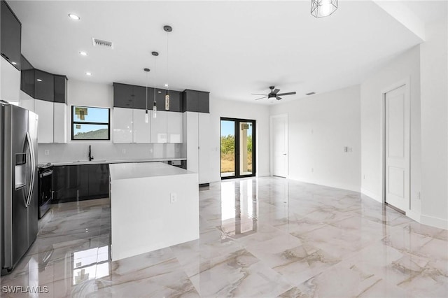 kitchen with ceiling fan, sink, decorative light fixtures, stainless steel fridge with ice dispenser, and a center island