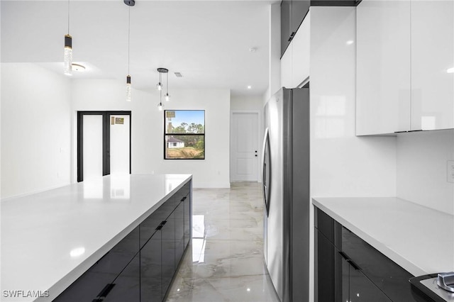 kitchen with stainless steel fridge, white cabinets, and decorative light fixtures