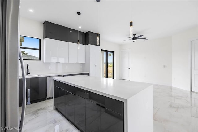 kitchen featuring white cabinets, hanging light fixtures, ceiling fan, a kitchen island, and stainless steel appliances