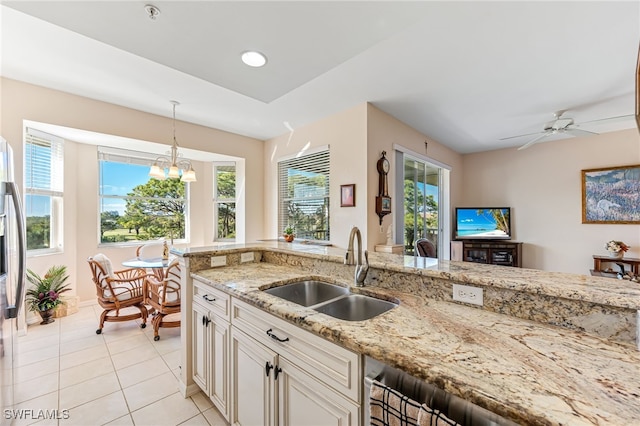 kitchen featuring light stone countertops, ceiling fan with notable chandelier, sink, light tile patterned floors, and hanging light fixtures