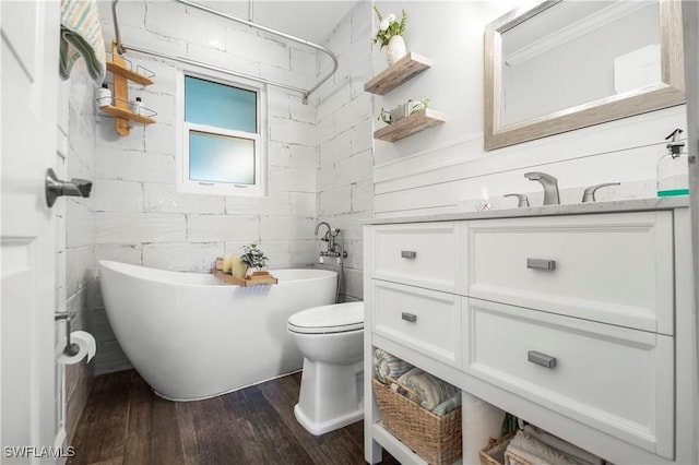 bathroom with hardwood / wood-style flooring, vanity, toilet, and a bath