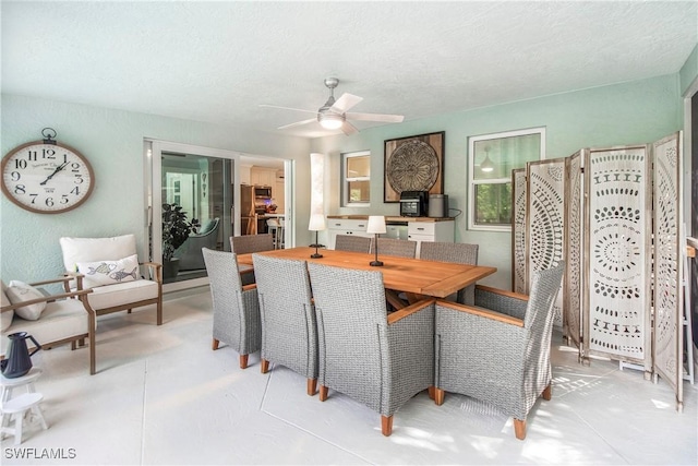 dining area featuring ceiling fan and a textured ceiling