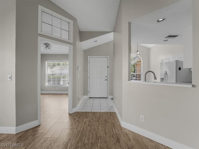 foyer featuring ceiling fan, lofted ceiling, sink, and light hardwood / wood-style flooring