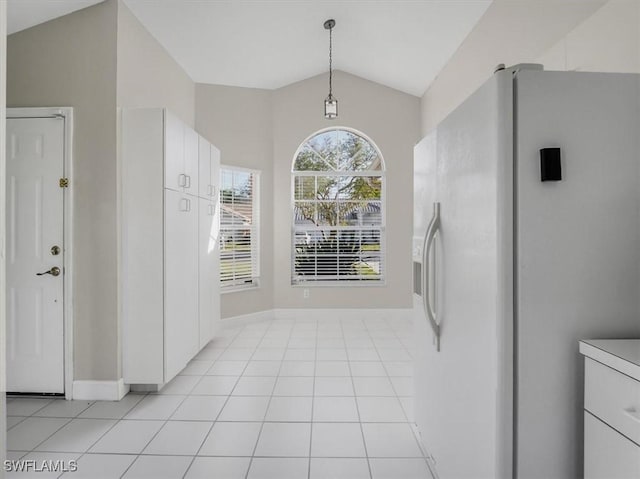 unfurnished dining area with light tile patterned floors and lofted ceiling