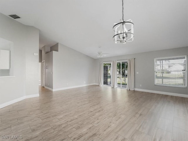 unfurnished living room with ceiling fan with notable chandelier and light hardwood / wood-style floors