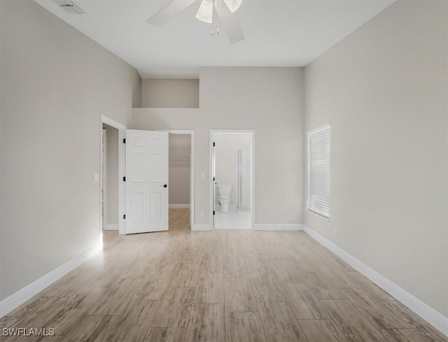 spare room featuring ceiling fan, light hardwood / wood-style flooring, and a high ceiling