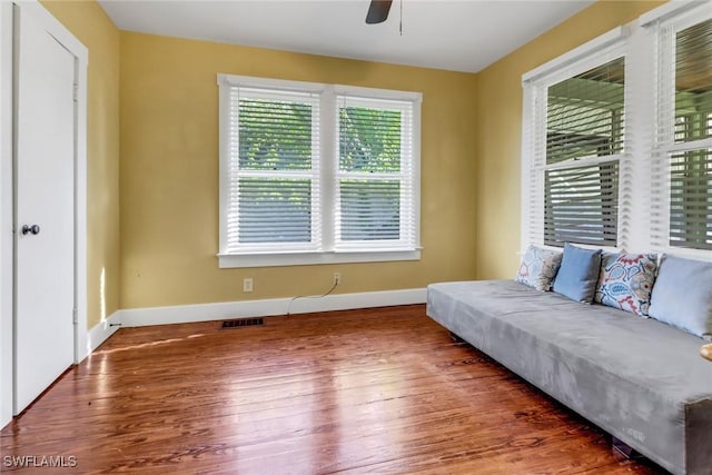 living area featuring ceiling fan and dark wood-type flooring