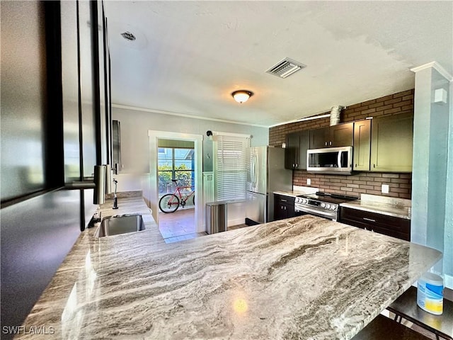 kitchen with light stone counters, a kitchen bar, backsplash, and appliances with stainless steel finishes