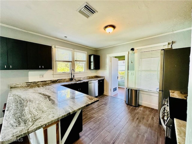 kitchen with light stone counters, sink, crown molding, and appliances with stainless steel finishes