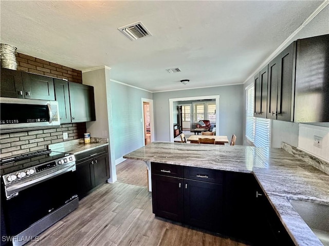 kitchen featuring kitchen peninsula, stove, light wood-type flooring, backsplash, and crown molding