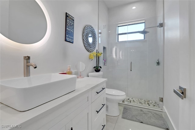 bathroom with tile patterned flooring, vanity, a shower with shower door, and toilet