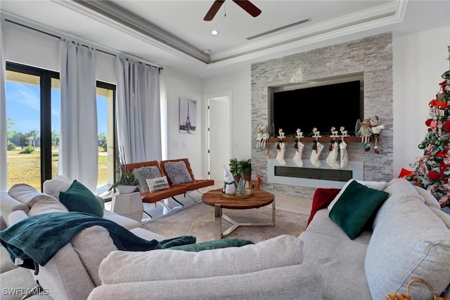 living room with a tray ceiling, crown molding, and ceiling fan