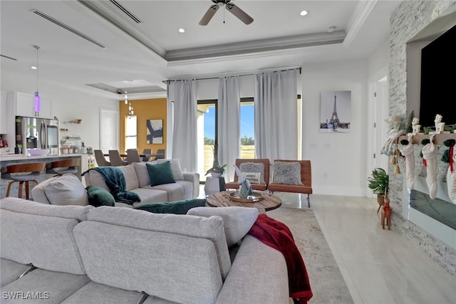 tiled living room featuring ceiling fan, ornamental molding, and a tray ceiling