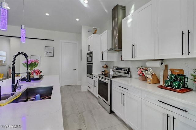 kitchen featuring pendant lighting, white cabinets, stainless steel appliances, and wall chimney range hood