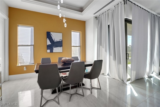 tiled dining area featuring a raised ceiling and ornamental molding