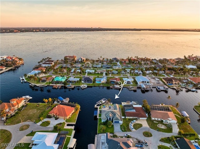 aerial view at dusk featuring a water view