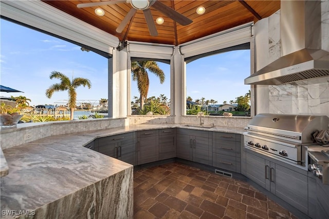 view of patio featuring an outdoor kitchen, a water view, sink, ceiling fan, and area for grilling